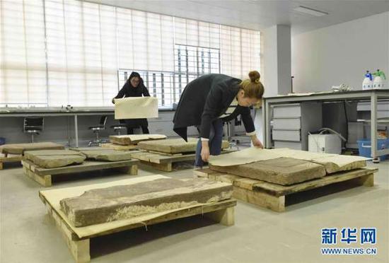 2月27日,成都考古研究所文物保护与修复中心工作人员在对清洗干净的墓志进行防尘保护。